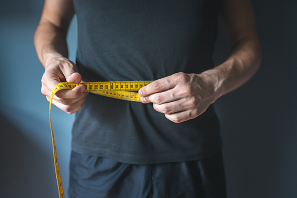 Man measures waist with tape measure