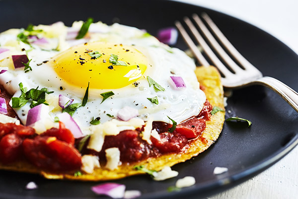 These healthier Huevos Rancheros nix the deep fried chips in favor of a single baked tortilla topped with a rich red chili sauce and a single sunny egg. 
