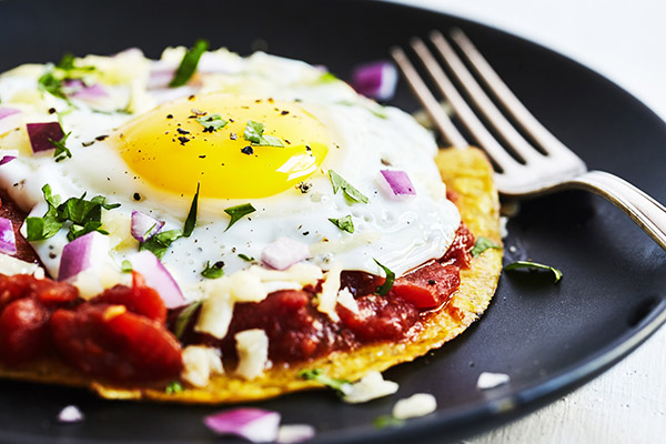 These healthier Huevos Rancheros nix the deep fried chips in favor of a single baked tortilla topped with a rich red chili sauce and a single sunny egg.