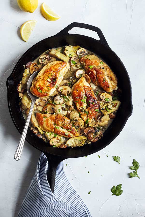 This healthier chicken piccata recipe is prepared in the classic style and topped with flavorful mushrooms, artichokes, and capers.