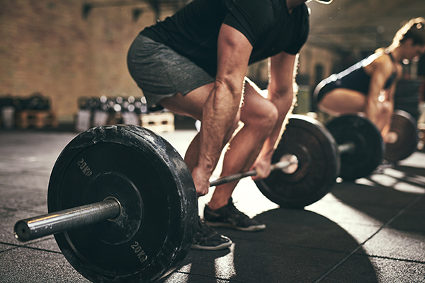 Man, woman doing deadlifts at gym.