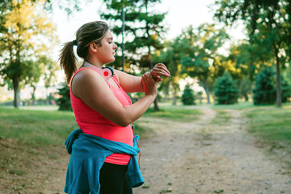 Overweight runner checking smart watch.