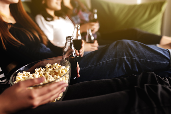 Friends sitting on couch eating popcorn