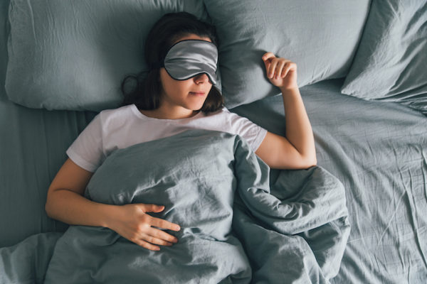 woman sleep in eye patch in grey bed | rest day