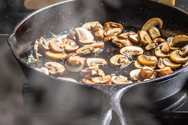 Sauteing sliced mushrooms in a cast iron skillet