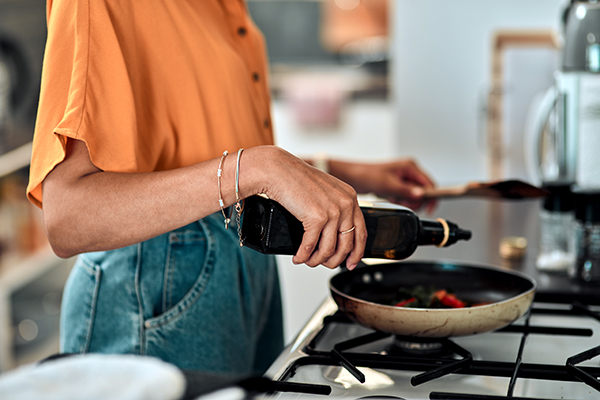 Woman pouring oil into a pan on stove