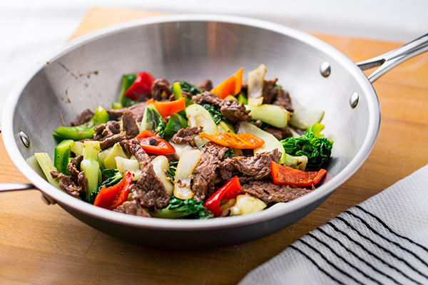 Wok stir-fried beef and vegetable on cutting board.