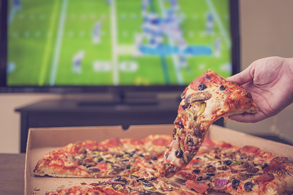 Man eating pizza while watching football on TV