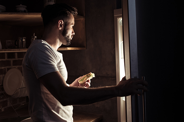 Man eating and looking in the fridge