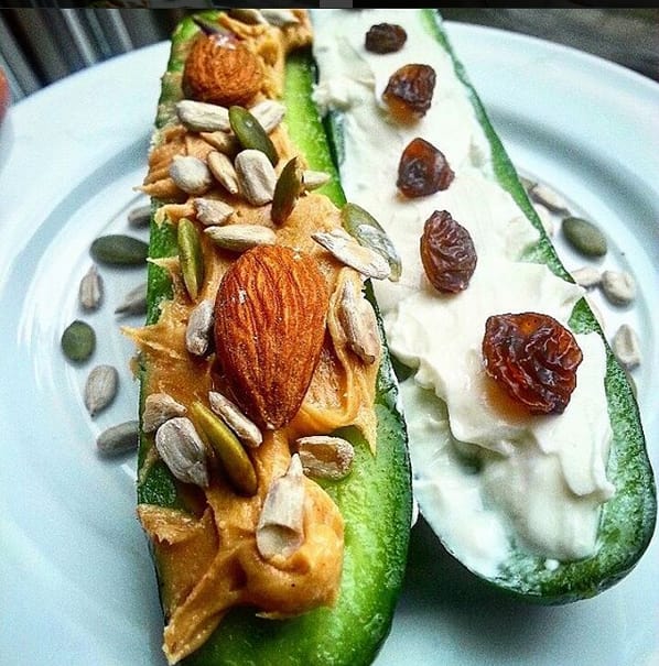 Meal prep snacks made with peanut butter and sunflower seeds on cucumber and ants on a log with raisins and cucumber