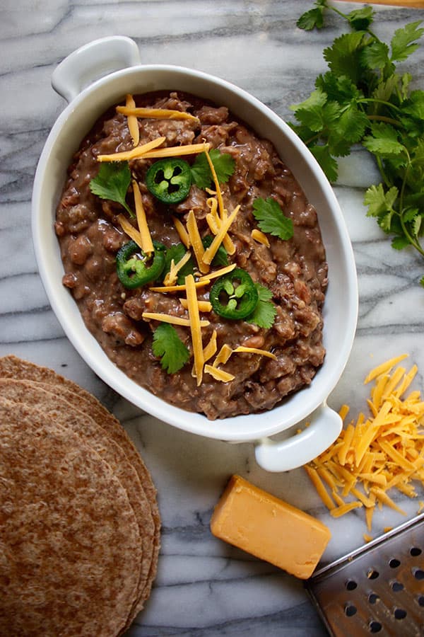 These delicious slow cooker refried beans combine onion, garlic, salt, pepper, and a dash of heat and freeze well for later too!