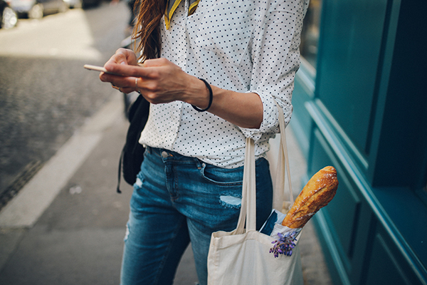 Woman texting with a shopping bag on her arm