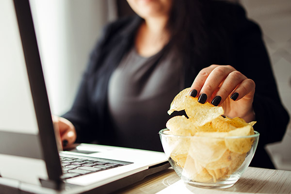 Woman snacking on potato chips while working