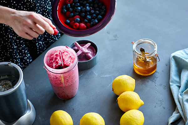 Woman putting berries into a shaker cup