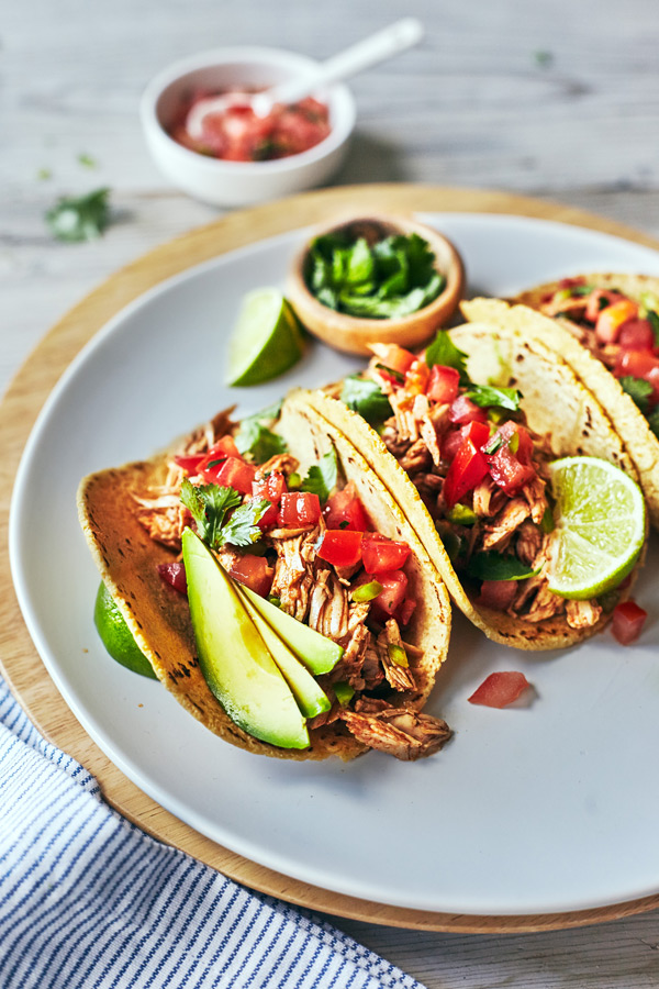 Bring the flavor of your favorite Mexican restaurant home with this healthy recipe for Slow Cooker Chicken Tacos with fresh tomatoes, lime, cilantro and avocado.