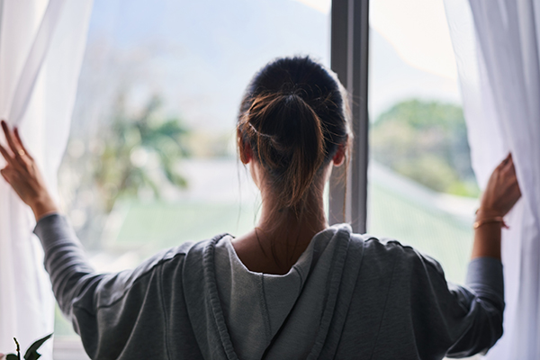 Woman opening curtains in the morning