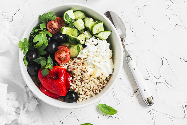 Bowl of quinoa salad with cucumbers, tomatoes, and red pepper