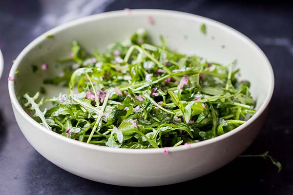 Arugula salad in a bowl with light dressing