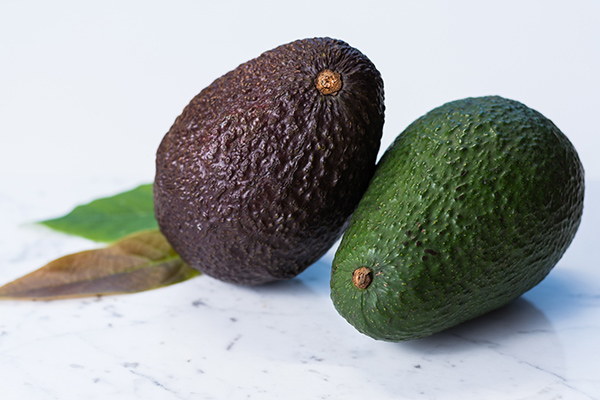 Green ripe avocado on white marble background