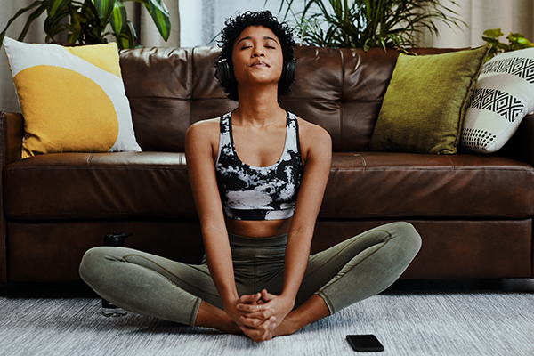young woman listening to music while meditating at home