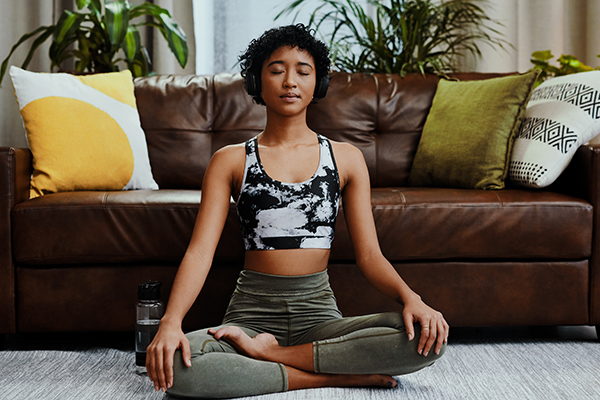 Woman meditating at home, listening to music