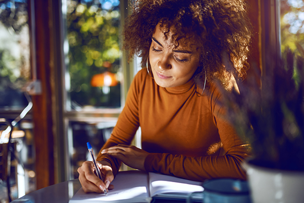 Woman writing in gratitude journal