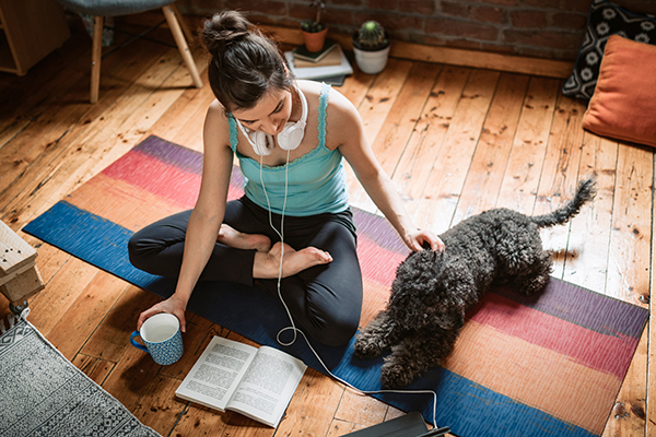 Woman sitting on yoga mat with dog