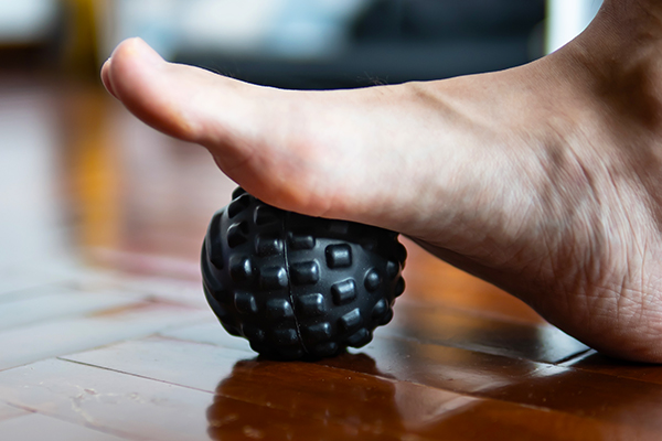 Foot on massage ball to relieve Plantar fasciitis or heel pain.