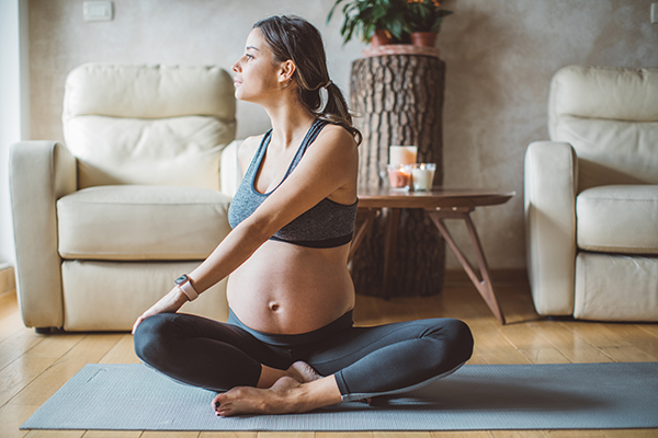 Young pregnant woman exercising at home.