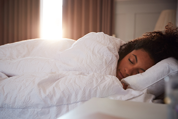 Woman sleeping as sun peeks through curtains