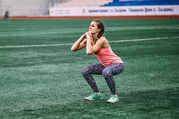 Woman doing a burpee on athletic field