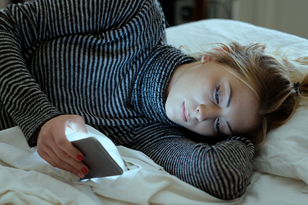 Woman scrolling through social media in bed