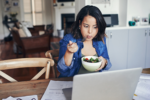 Woman eating salad while working from home