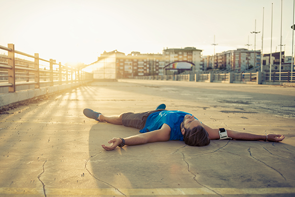 male runner lying on the ground exhausted