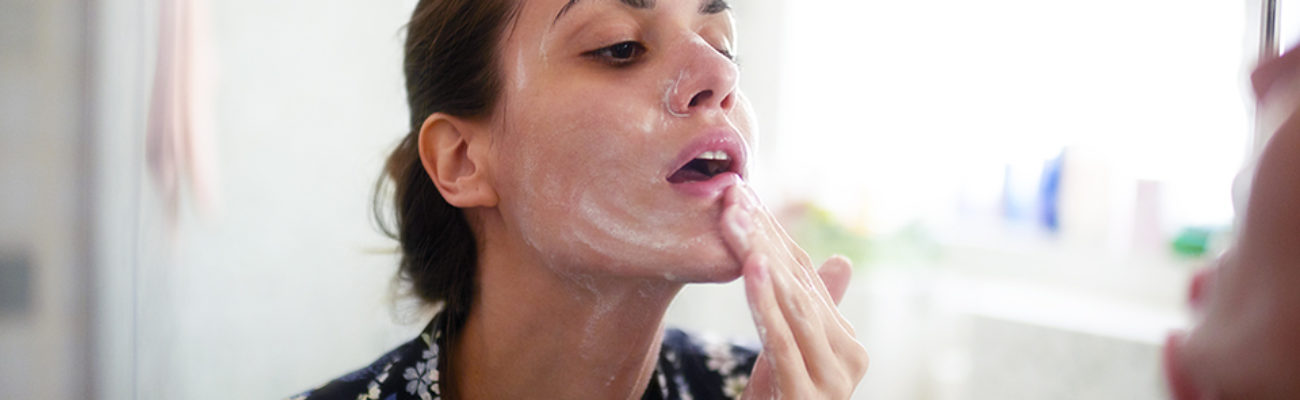Woman using cleanser on her face at home
