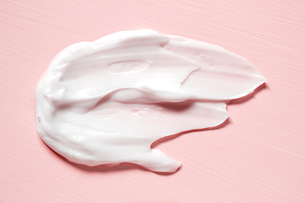 Smear of moisturizer in pink background. 