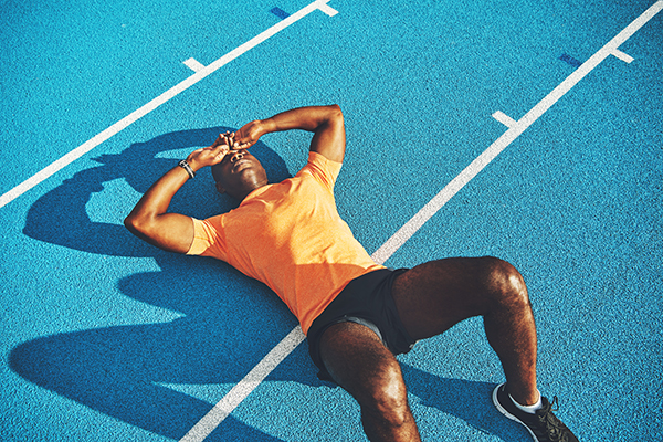 Exhausted young man lying down on running track