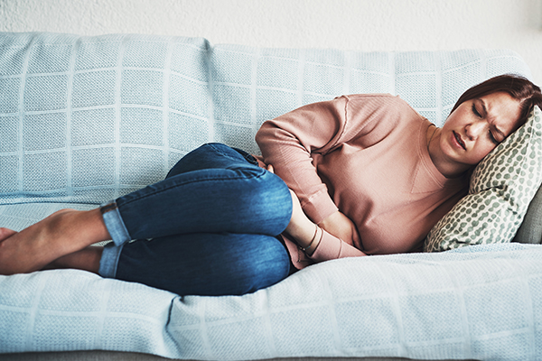 Woman lying on couch with stomach ache