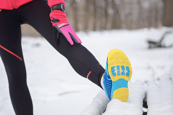 Runner stretching leg on snowy bench