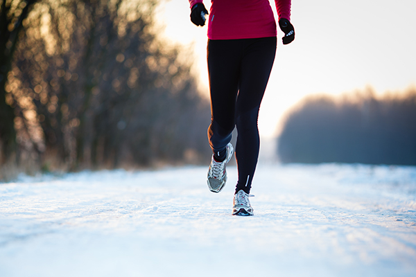 Shot of lower legs of runner jogging on snowy road