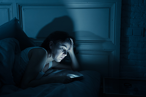 Woman checking smartphone in bed