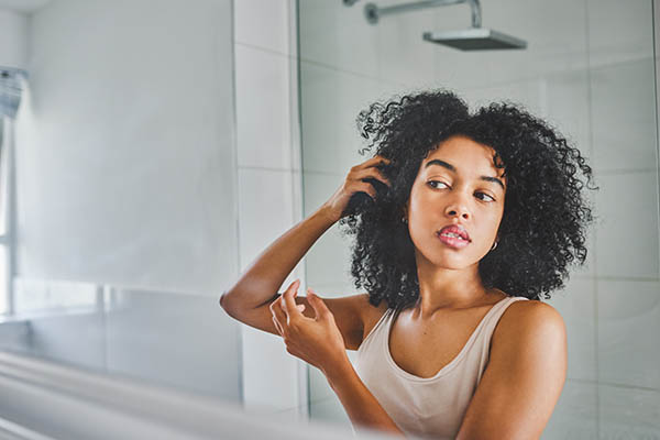 Woman looking at hair in bathroom mirror