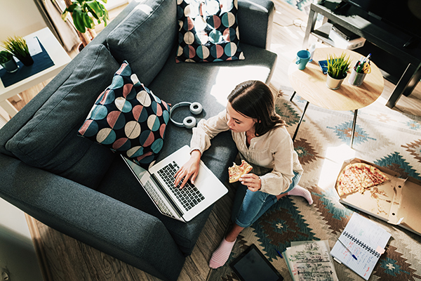 Woman eating pizza and working on computer