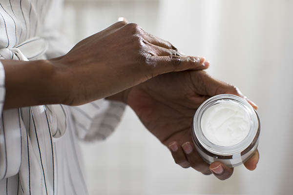 woman putting lotion on hand