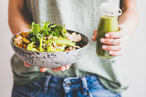 Woman holding salad and green shake