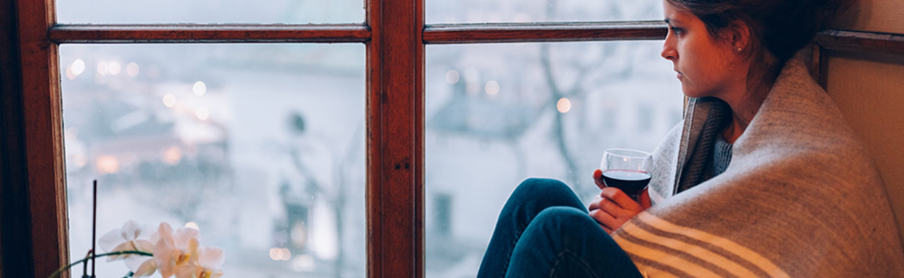 Woman sitting near window drinking wine