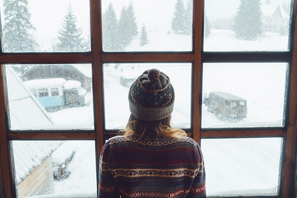 Woman looking out window at winter landscape