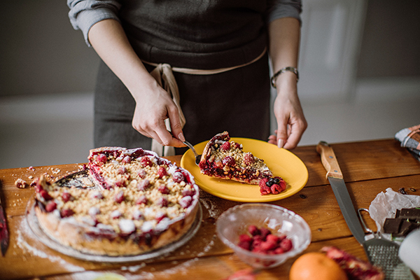 Woman cutting a slice out of a berry pie