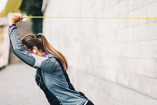 Woman using resistance band anchored to wall