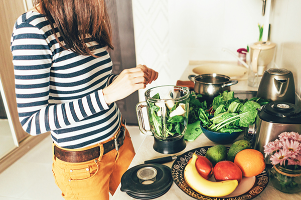 Woman in her kitchen preparing a smoothie.